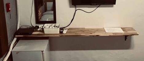 Une chambre d’hôtel équipée d’un lit, d’un bureau avec un téléviseur à écran plat, d’un miroir et d’un climatiseur fixé au mur.