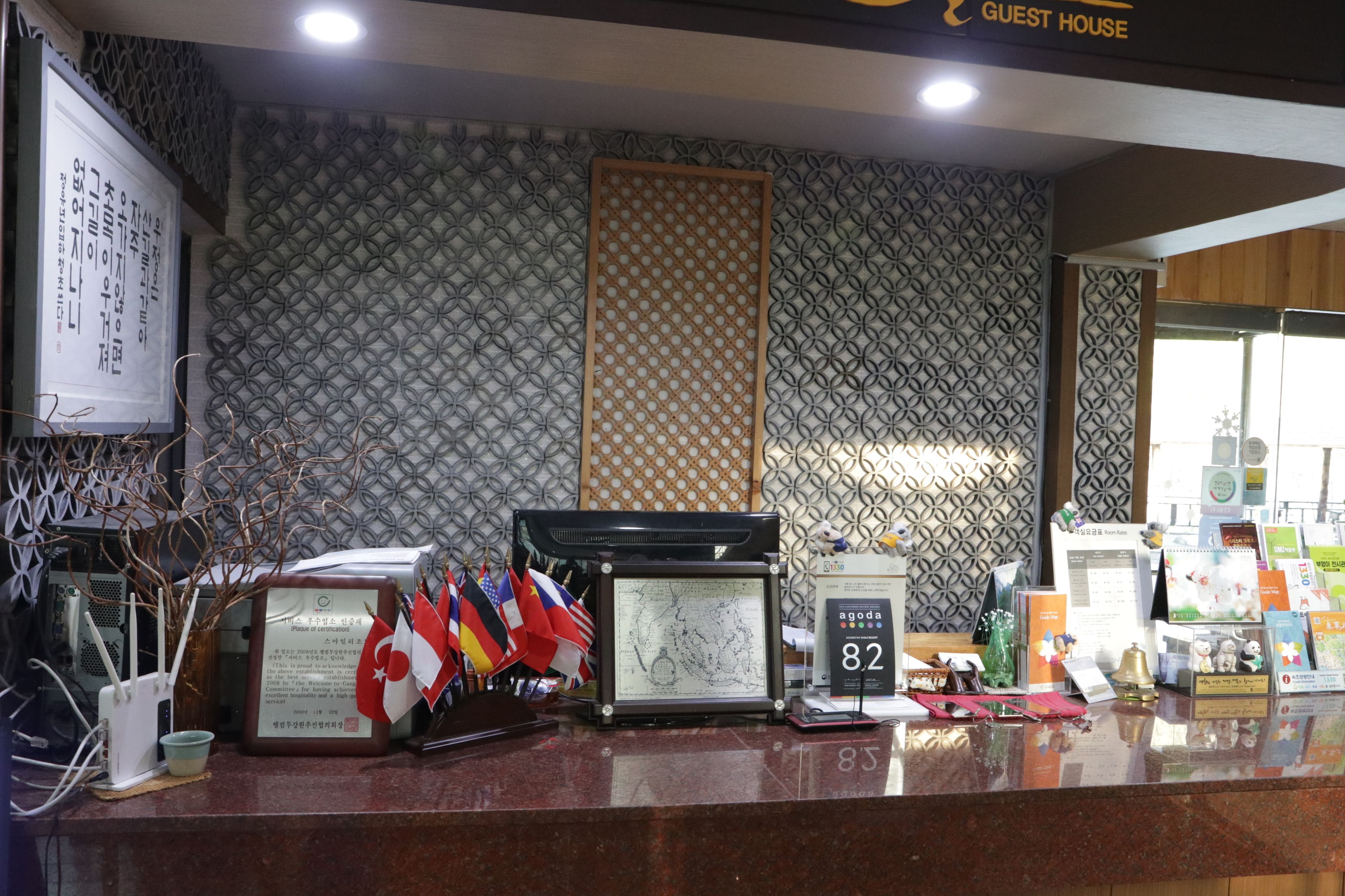 A reception desk with a patterned wall, a clock, and various items including flags and a small bell.