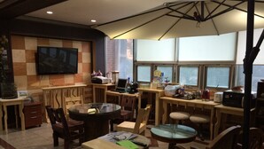 A cozy room with a TV, wooden furniture, a round table, and a large window.