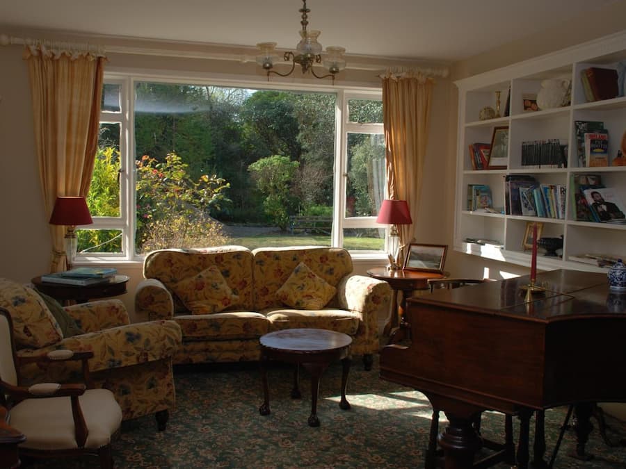 A cozy living room with a sofa, armchairs, a coffee table, and a bookshelf.