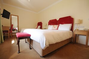 A hotel room with a large bed, a desk, a chair, a TV mounted on the wall, and a mirror. - Casey's Hotel Glengarriff (Glengarriff)