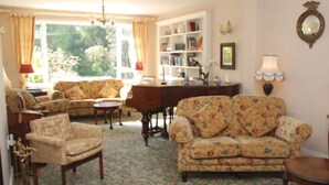 Un salón acogedor con sofás de estampado floral, una mesa de centro de madera y una estantería.