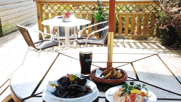 Una mesa con platos de mejillones y arroz, una jarra de cerveza y una cesta de pan.