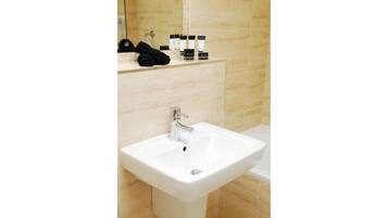 A bathroom with a white sink, a mirror, and toiletries on the countertop.