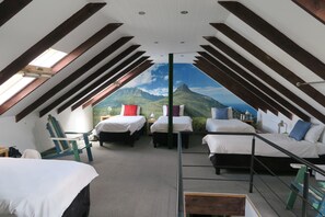 Una camera da letto con quattro letti disposti a ferro di cavallo, una cupola luminosa e un murale raffigurante montagne.
