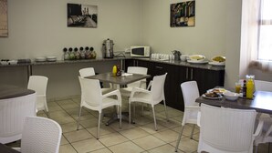 Comedor con mesa, sillas, microondas y diversos alimentos.