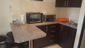 Una cocina con encimera de granito, dos hornos empotrados, un microondas, un fregadero y muebles oscuros.