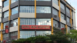 Un immeuble à plusieurs étages, avec une enseigne indiquant « HÔTEL IPOH BOUTIQUE » et, en dessous, une autre enseigne indiquant « PIZZA Hut ».