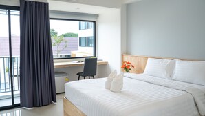 A modern hotel room with a large bed, a desk, and a view of buildings outside. - Meesuk ChiangRai Hotel, SHA Certified (Chiang Rai)