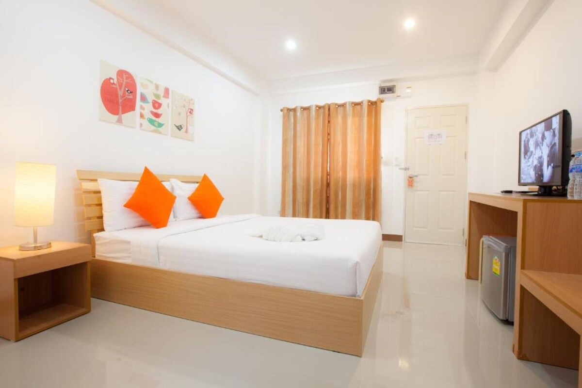 Habitación de hotel con cama, televisor, refrigerador y puerta.
