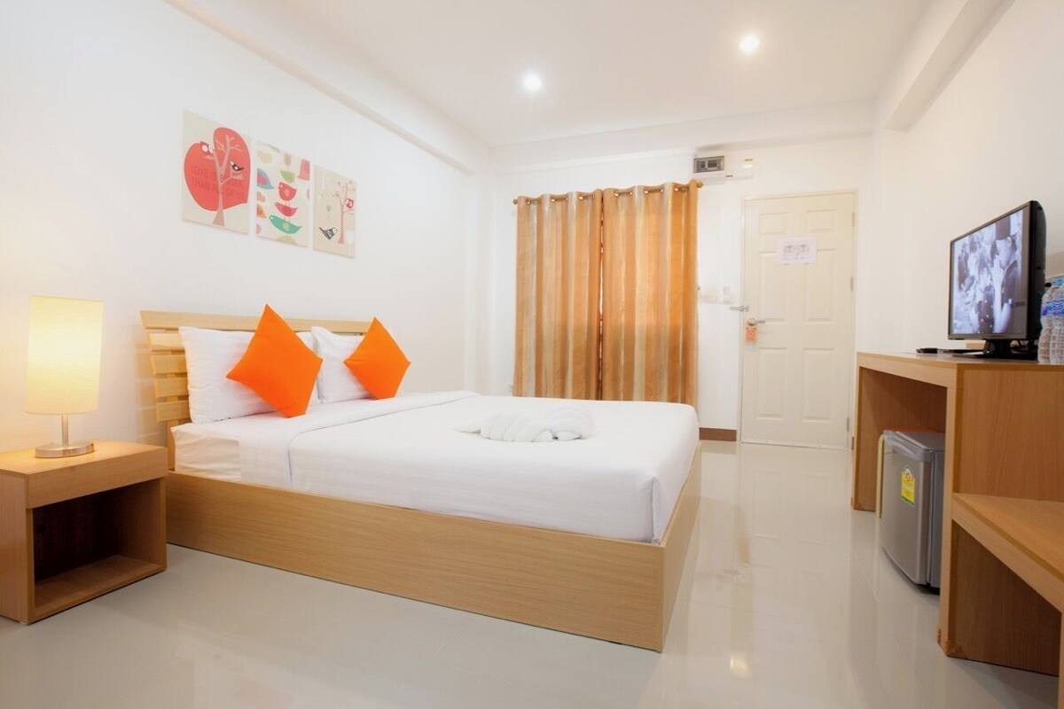 A hotel room with a bed, a TV, a desk, and a door.
