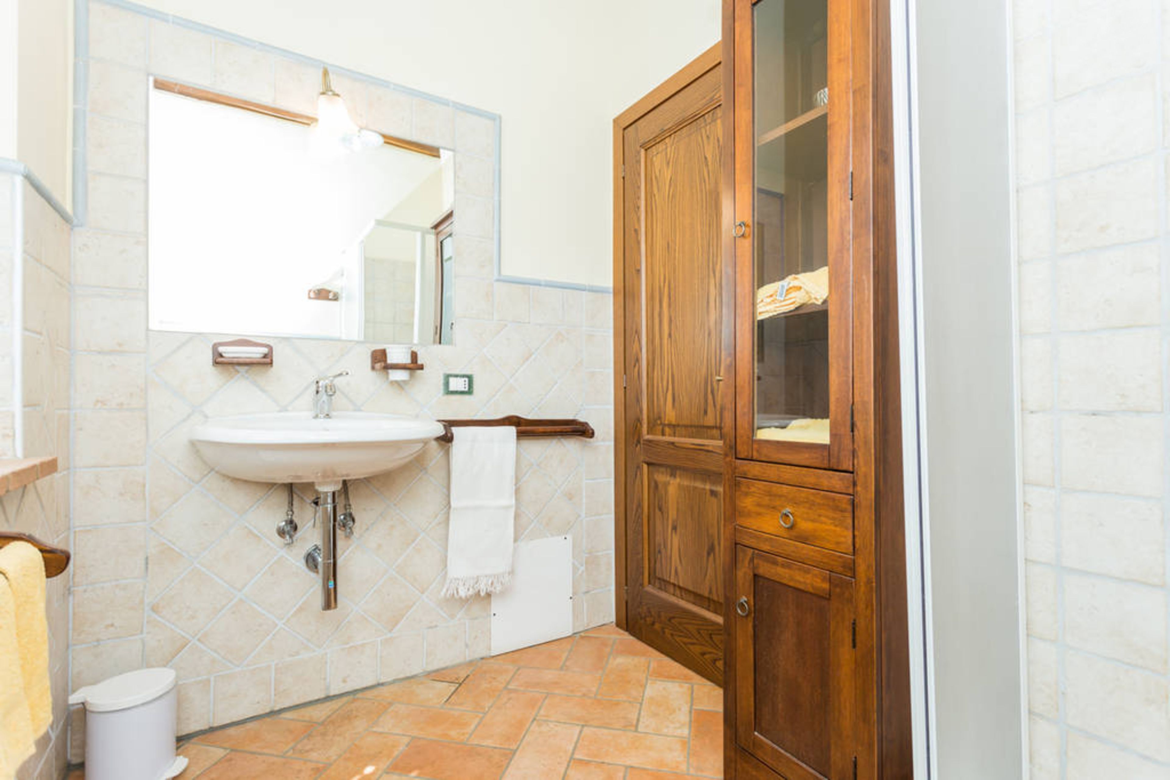 A bathroom with a sink, mirror, towel rack, and wooden cabinet.