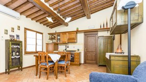 Une cuisine spacieuse avec des meubles en bois, une table à manger avec des chaises et un canapé bleu dans le salon.