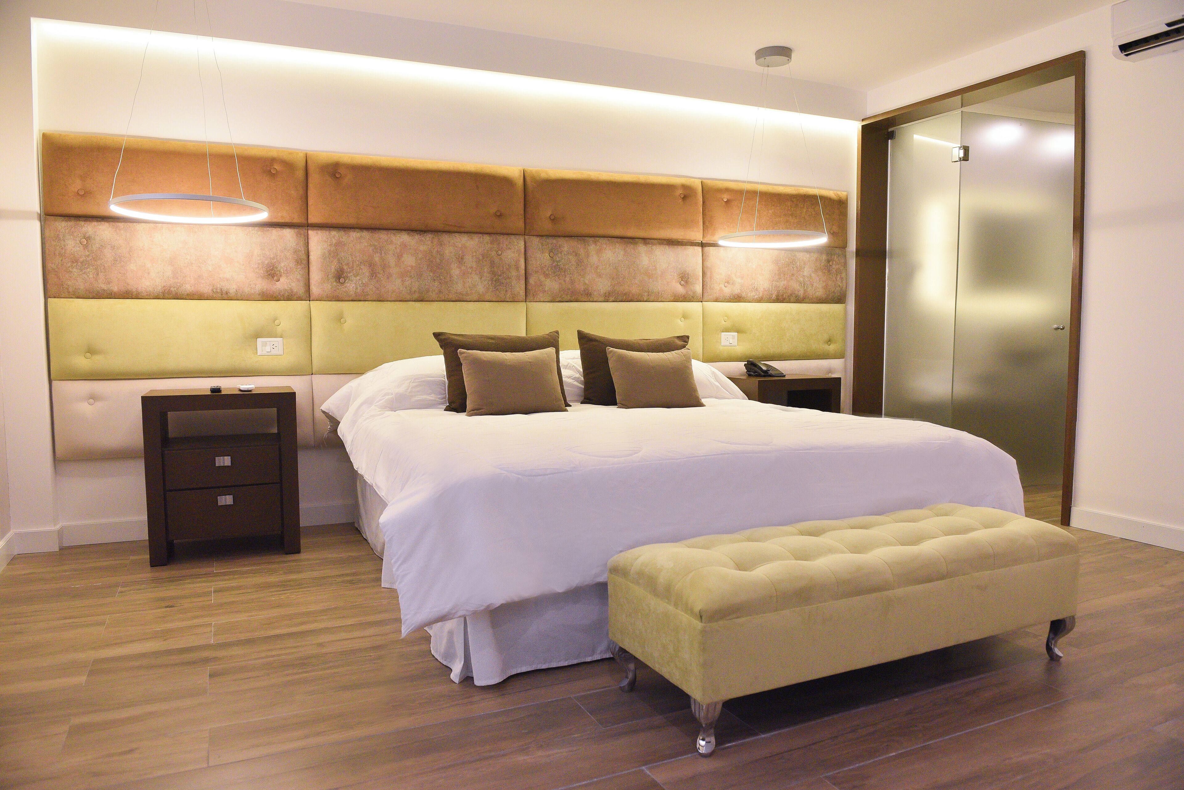 Un dormitorio moderno con una cama grande, una mesita de noche, un banco y una puerta corredera.