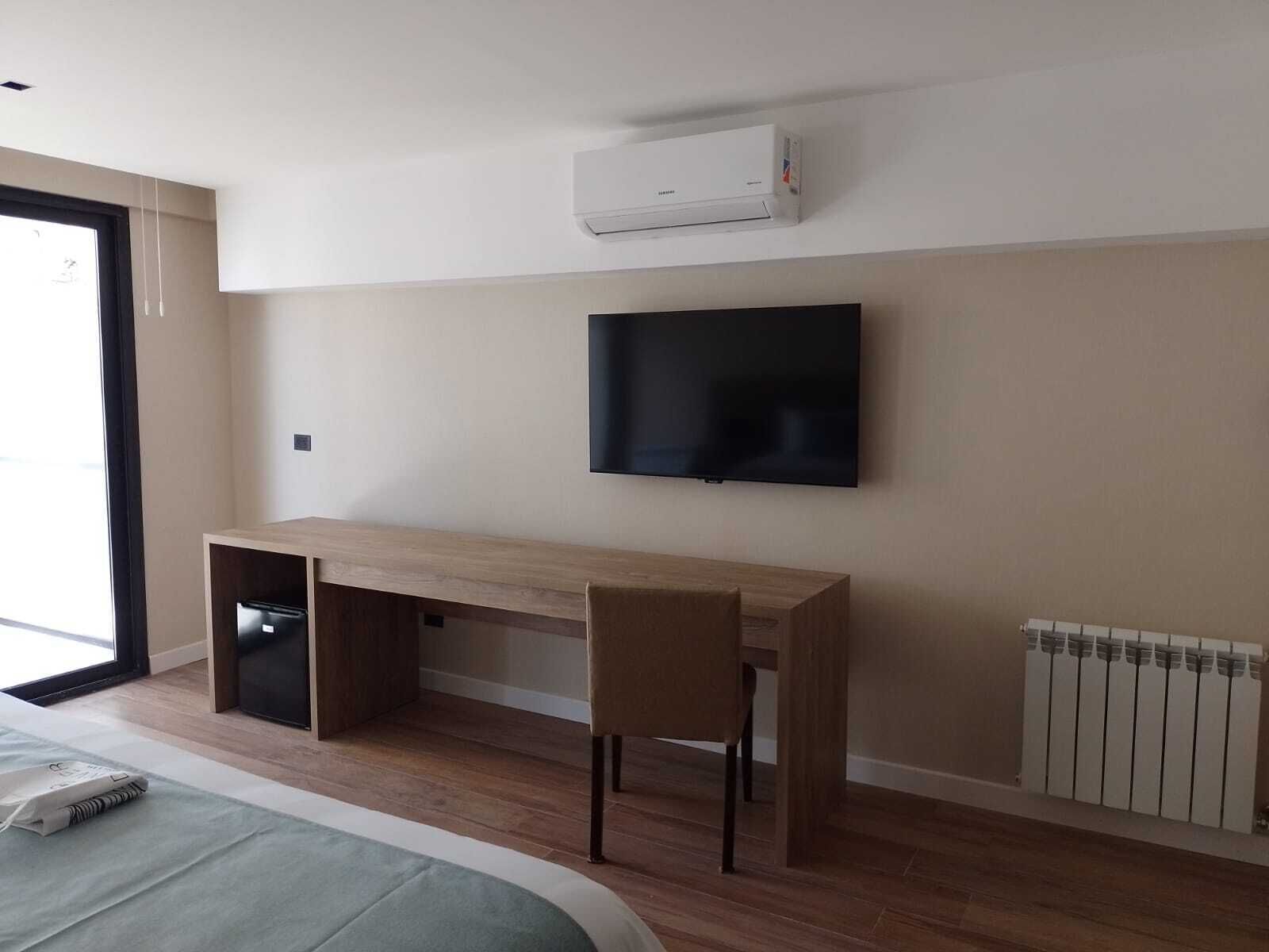 Une chambre moderne dotée d’un bureau en bois, d’un téléviseur à écran plat, d’un climatiseur et d’un radiateur.