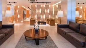 A modern lobby with a central coffee table, sofas, and a wooden wall with a clock. - Hotel Denver (Mar del Plata)