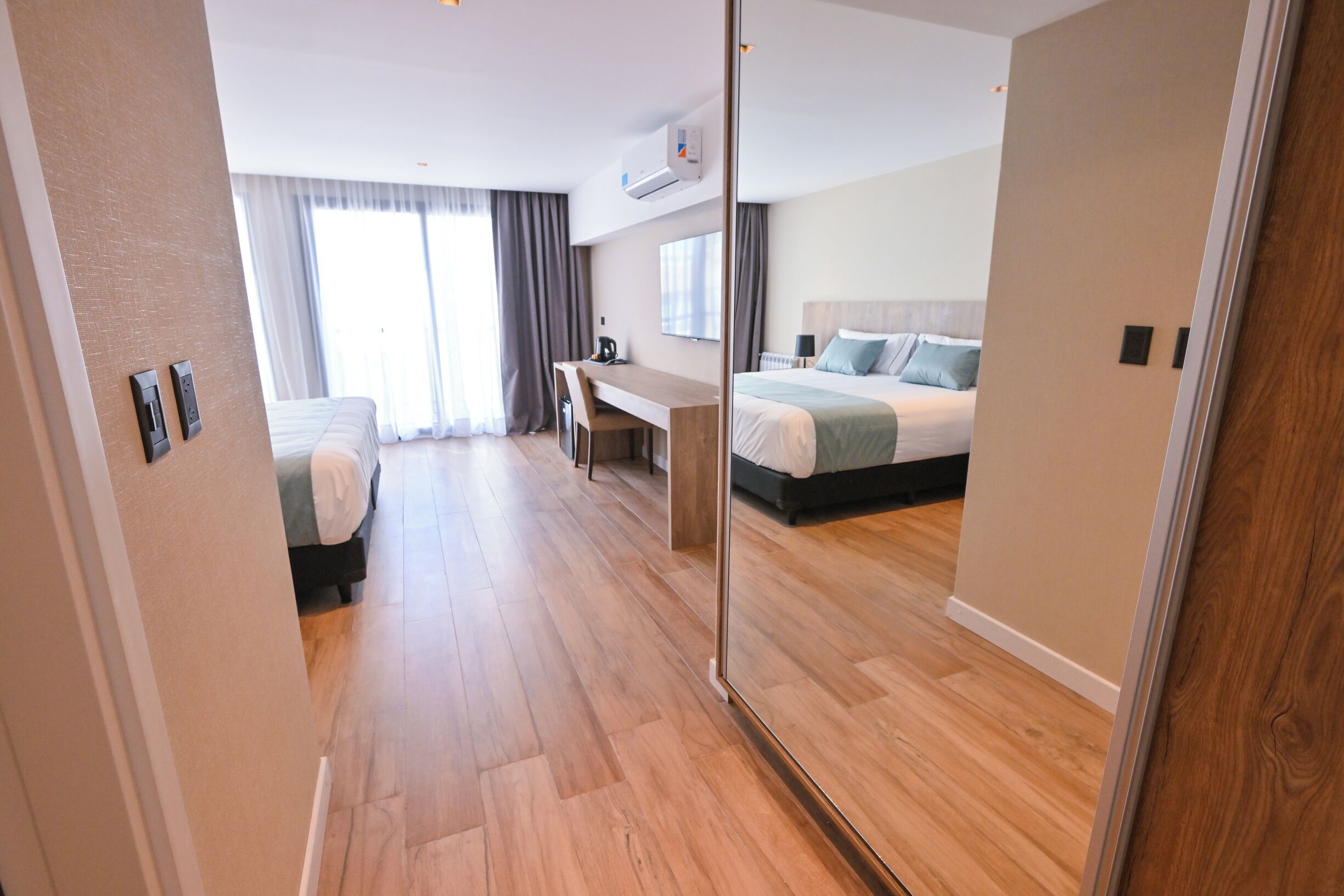 A modern hotel room with a large bed, a desk, and a seating area.