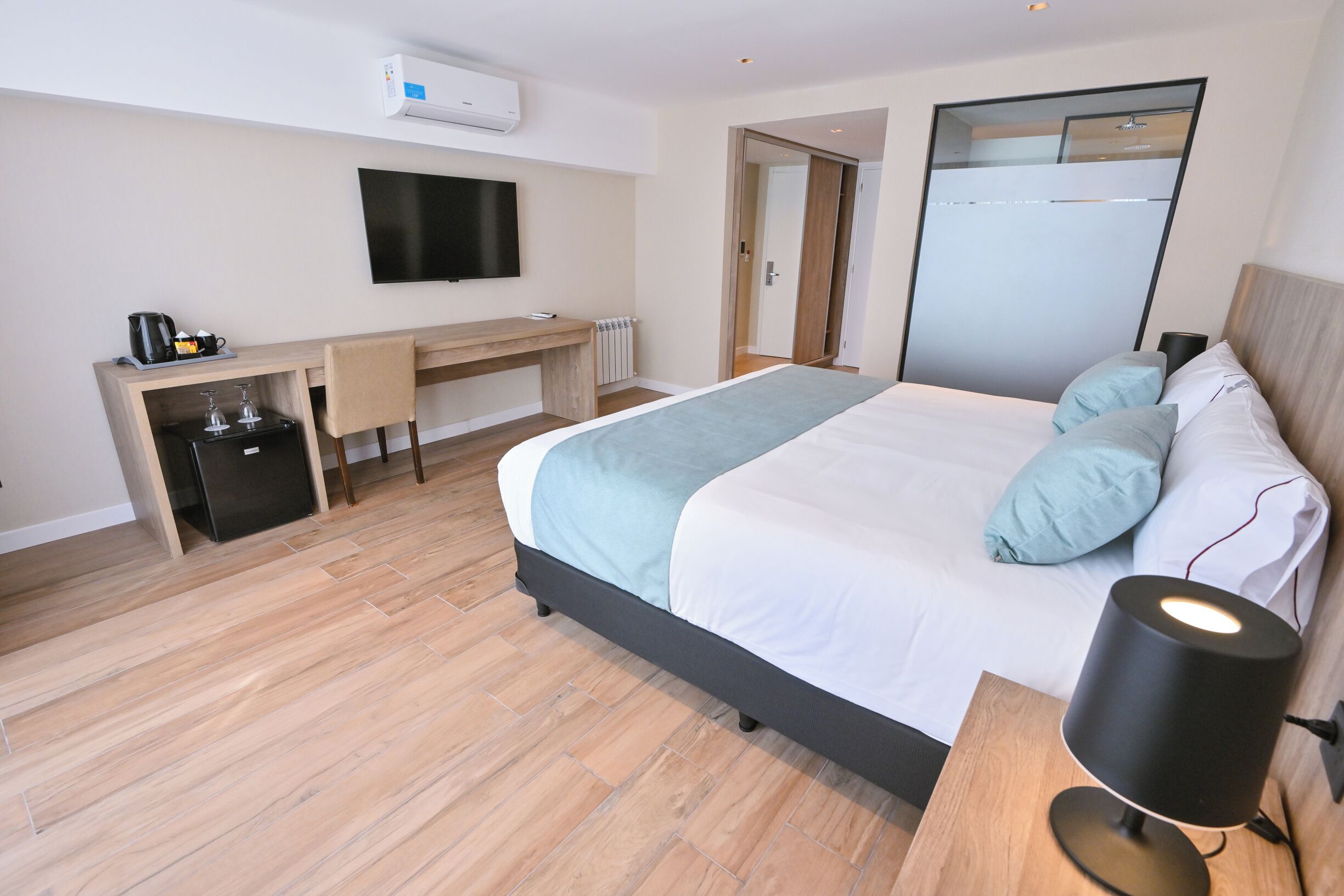 Una habitación de hotel moderna con cama, mesita de noche, escritorio y televisión de pantalla plana.