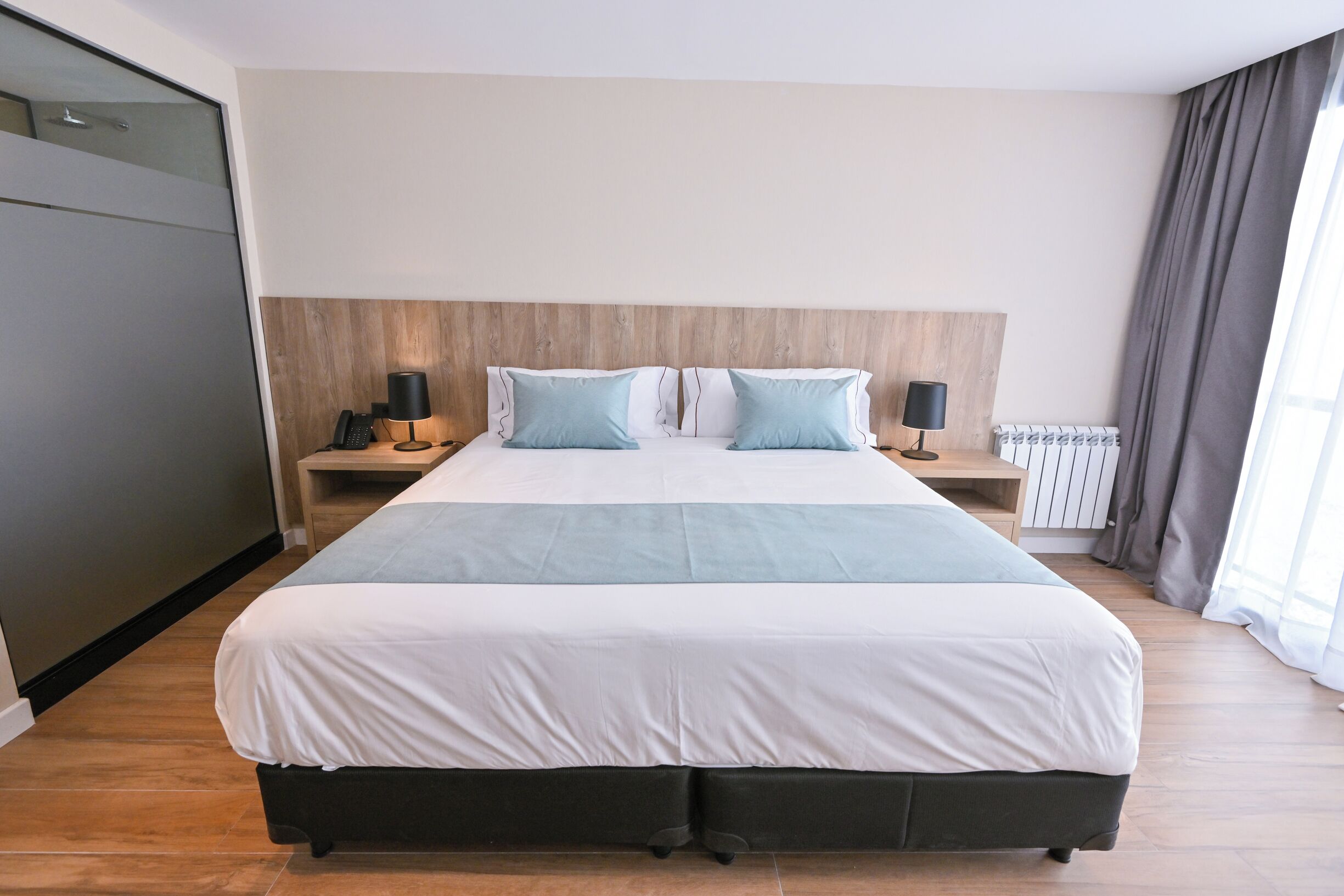 Ein großes Bett mit Holz-Kopfstütze, zwei Nachttische mit Lampen und ein Heizkörper.