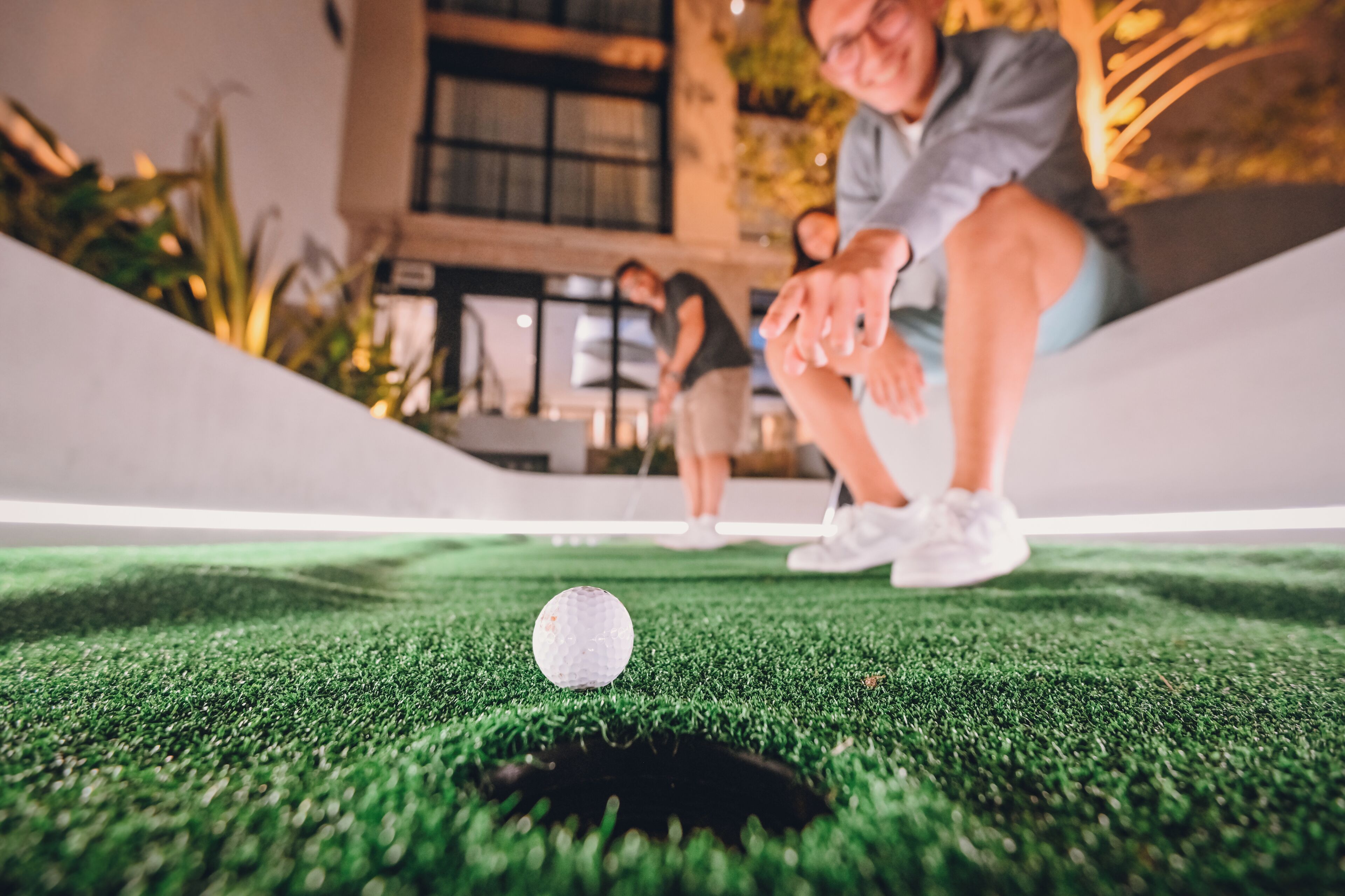 A golf ball on a green surface with a hole nearby.