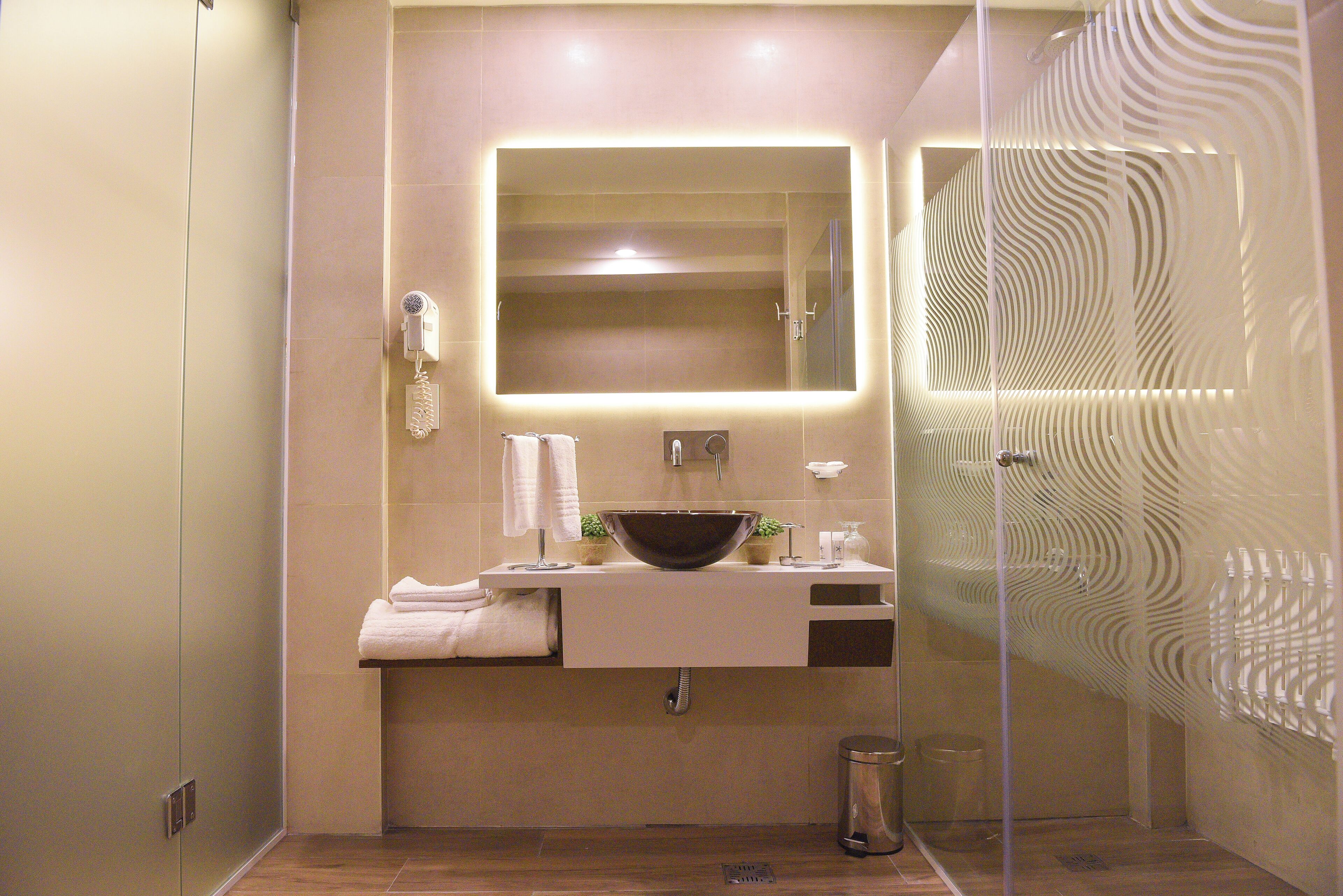 Une salle de bain moderne avec un grand miroir, un lavabo sur colonne et une cabine de douche en verre.