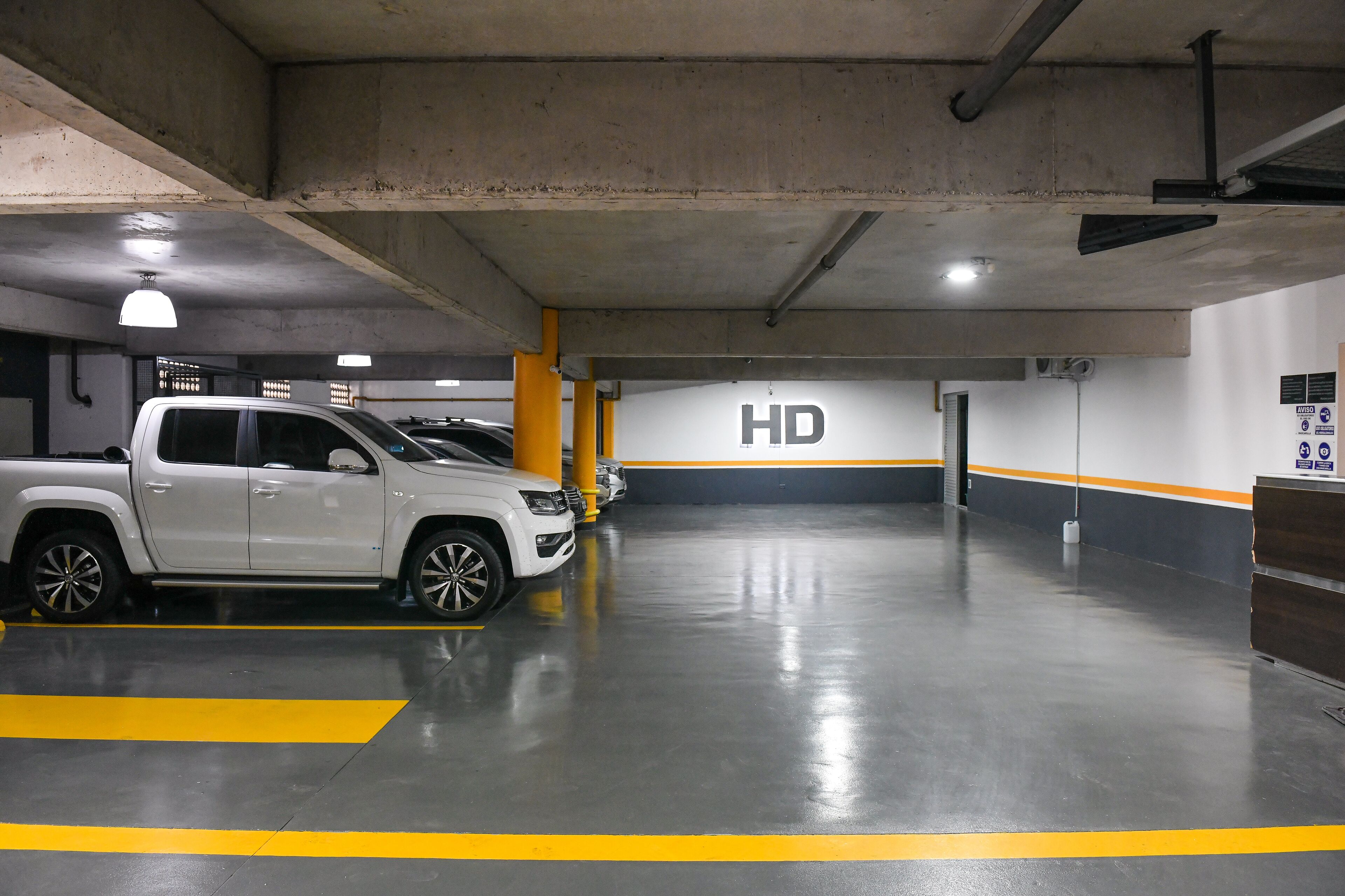 A parking garage with a white SUV parked in a bay marked 'HD'.