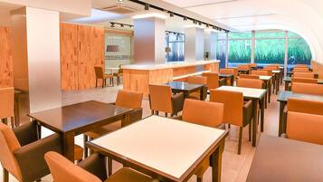 Un restaurante moderno con detalles de madera, una zona de bar y vistas a zonas verdes a través de grandes ventanales.