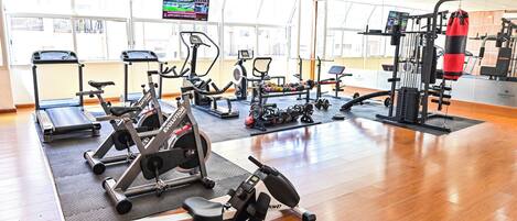 Een goed uitgeruste sportschool met cardioapparaten, krachtstations en een bokszak.