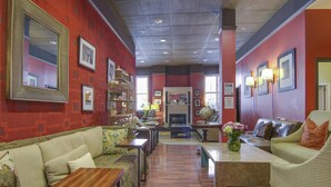 A hotel lobby with a red and grey color scheme, featuring a sofa, armchairs, a coffee table, and a fireplace. - Adelaide Hostel (San Francisco)