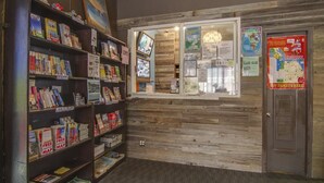 A bookstore with wooden shelves filled with books and a glass display case with maps and travel information. - Adelaide Hostel (San Francisco)
