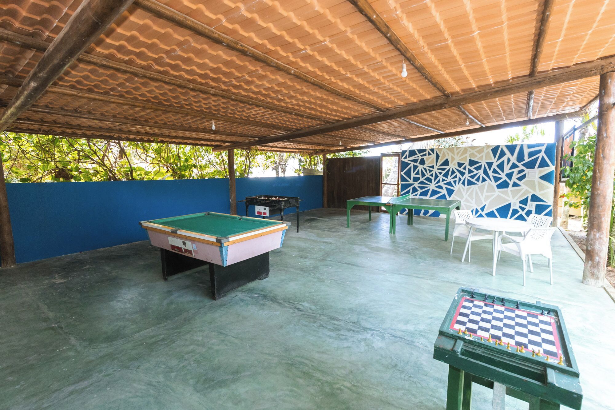 An outdoor recreational area with a pool table, a billiards table, and a foosball table.