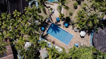 An aerial view of a swimming pool surrounded by palm trees and outdoor seating areas.