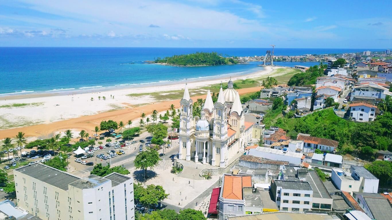 Un paisaje urbano costero con una catedral destacada, una playa y una mezcla de edificios residenciales y comerciales.