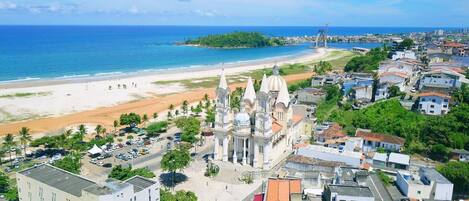 A coastal cityscape with a prominent cathedral, a beach, and a mix of residential and commercial buildings.