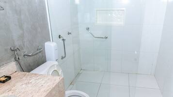 A bathroom with a toilet, a shower stall, and a marble countertop.