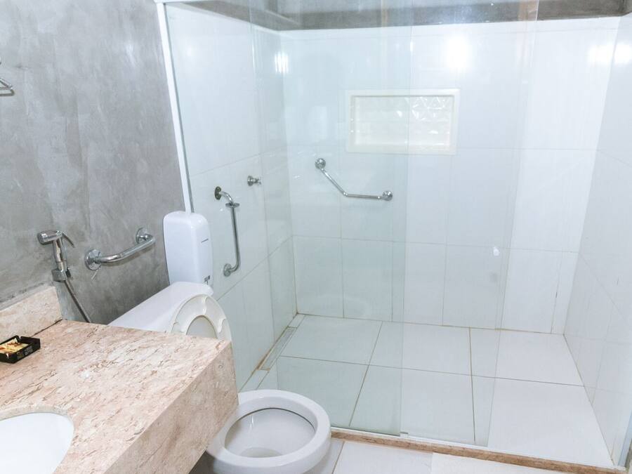 A bathroom with a toilet, a shower stall, and a marble countertop.