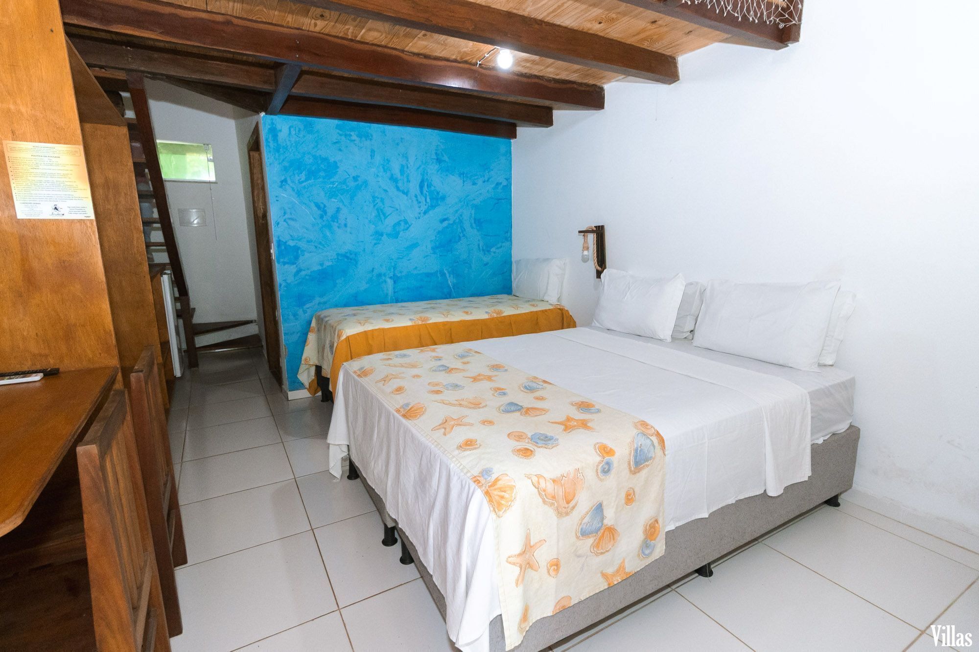 Une chambre avec deux lits, un plafond en bois et un mur d’accent bleu.