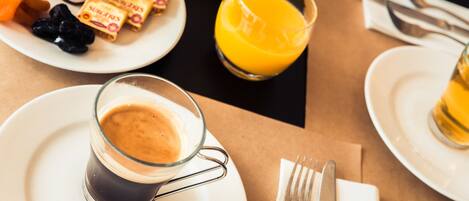 A breakfast setting with a cup of coffee, orange juice, and various condiments on a table.