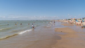 A beach with people swimming and walking along the shore.