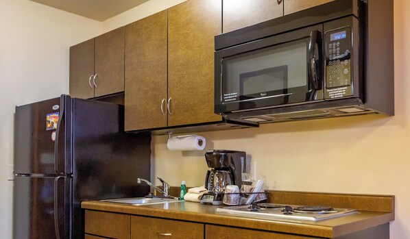 A compact kitchen with a refrigerator, microwave, and coffee maker.