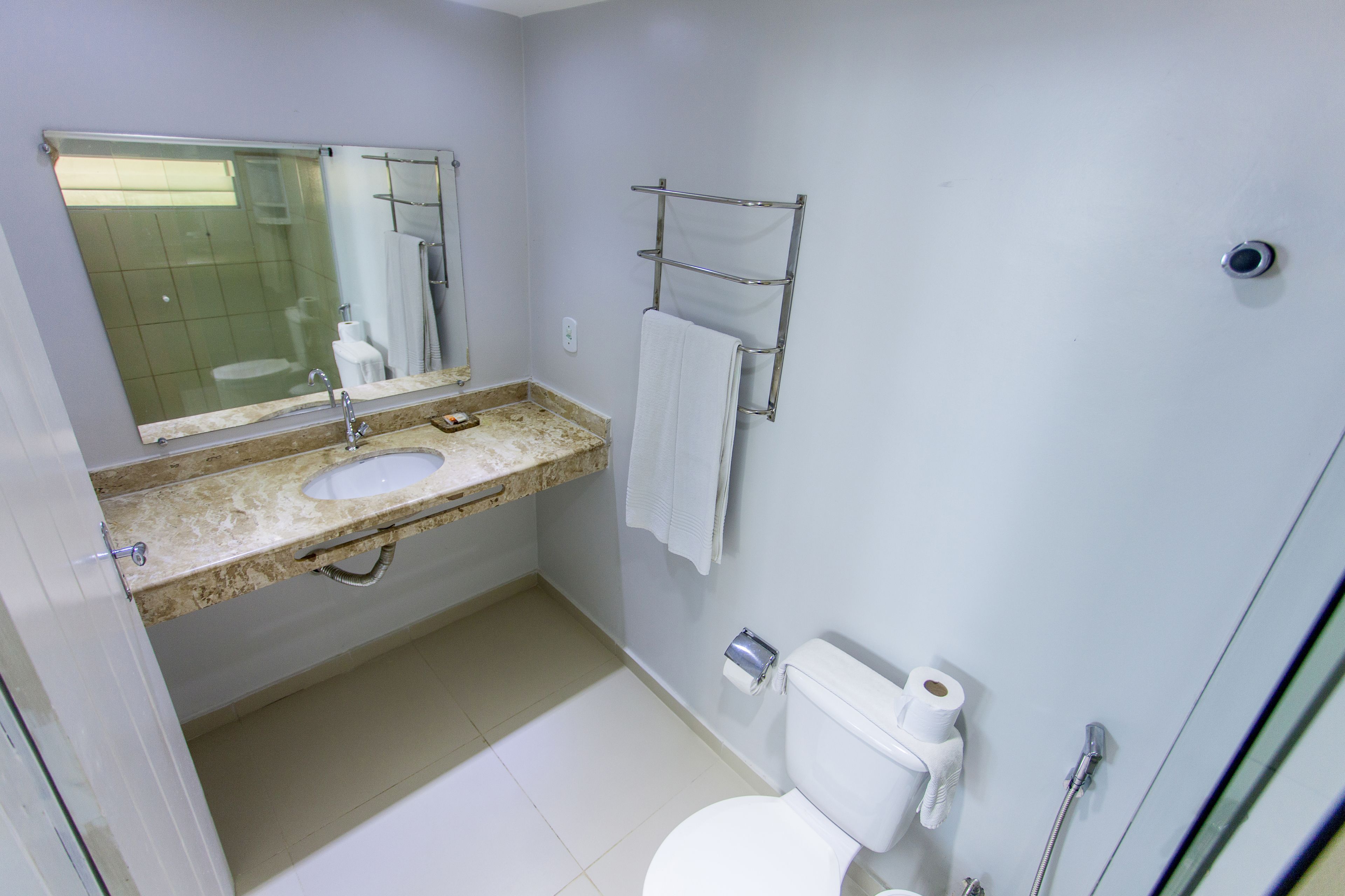 Een badkamer met wastafel, spiegel, handdoekhouder, toilet en douche.