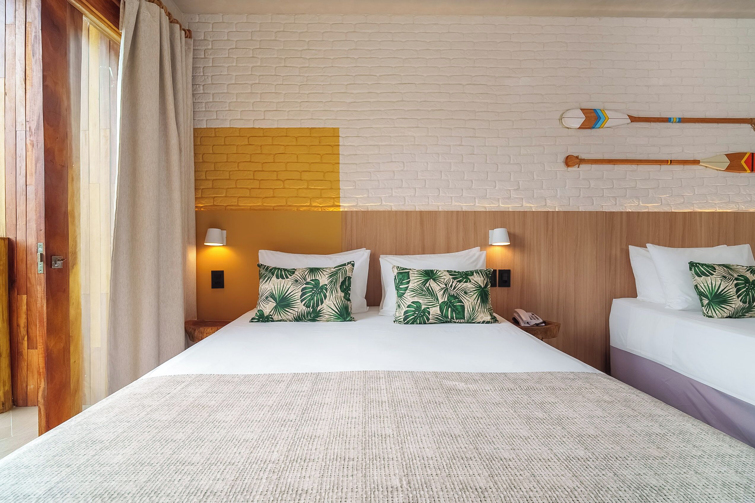 Una habitación de hotel con dos camas, una pared de ladrillo y un cabecero de madera.