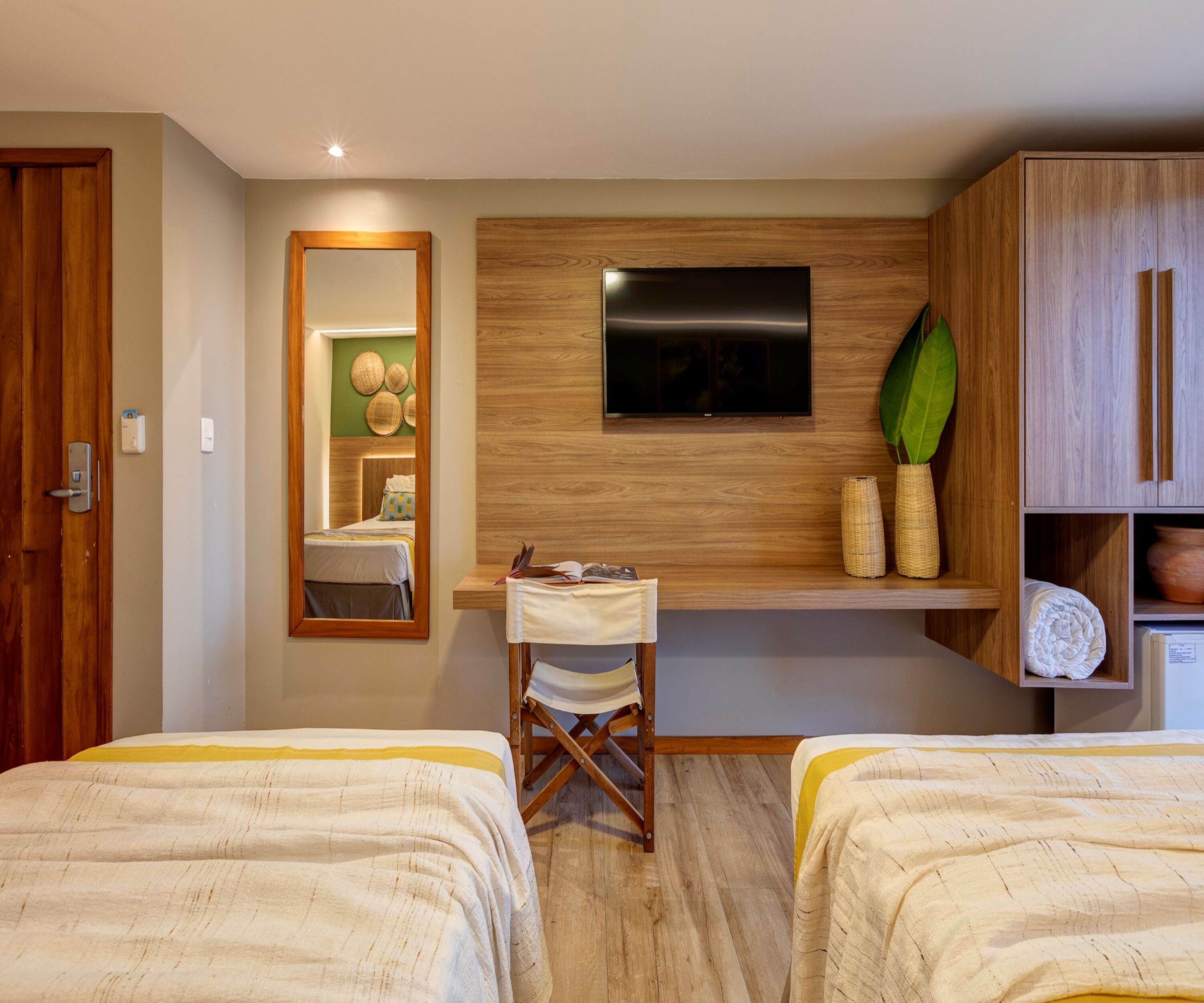 Ein Hotelzimmer mit zwei Betten, einem Schreibtisch, einem Fernseher und einem Kleiderschrank.