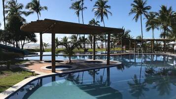 A pool area with a covered seating area and palm trees in the background.
