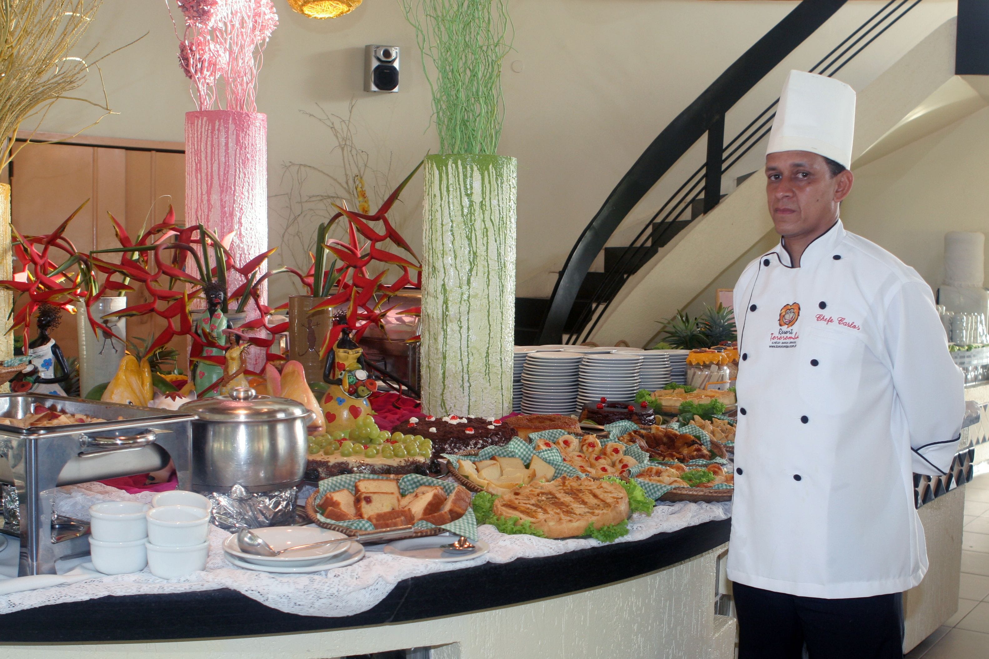 A buffet setup with various food items and a chef in uniform.