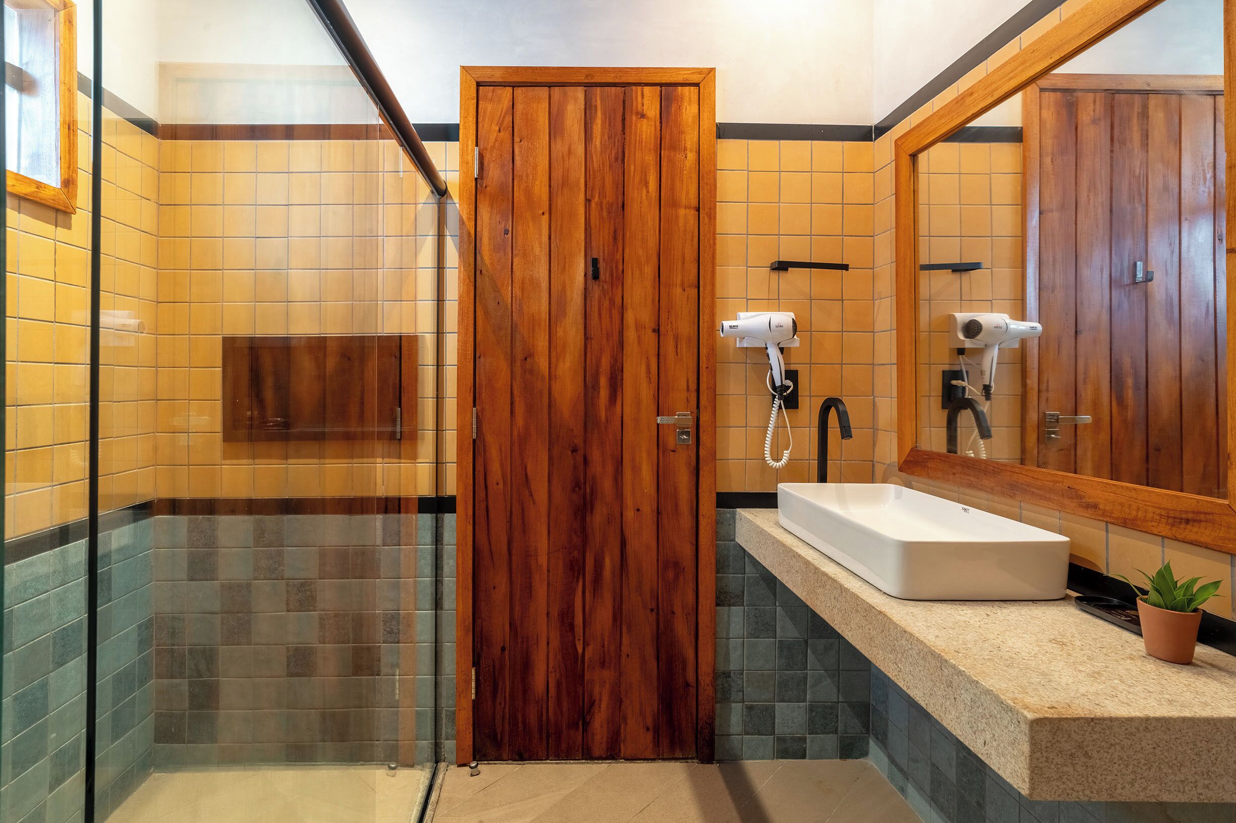 A bathroom with a wooden door, a white sink, and a glass shower enclosure.