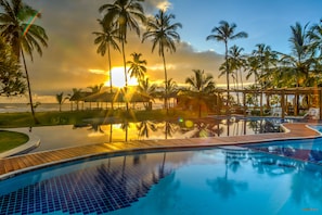 Un espace piscine agrémenté de palmiers et offrant une vue sur le coucher du soleil.