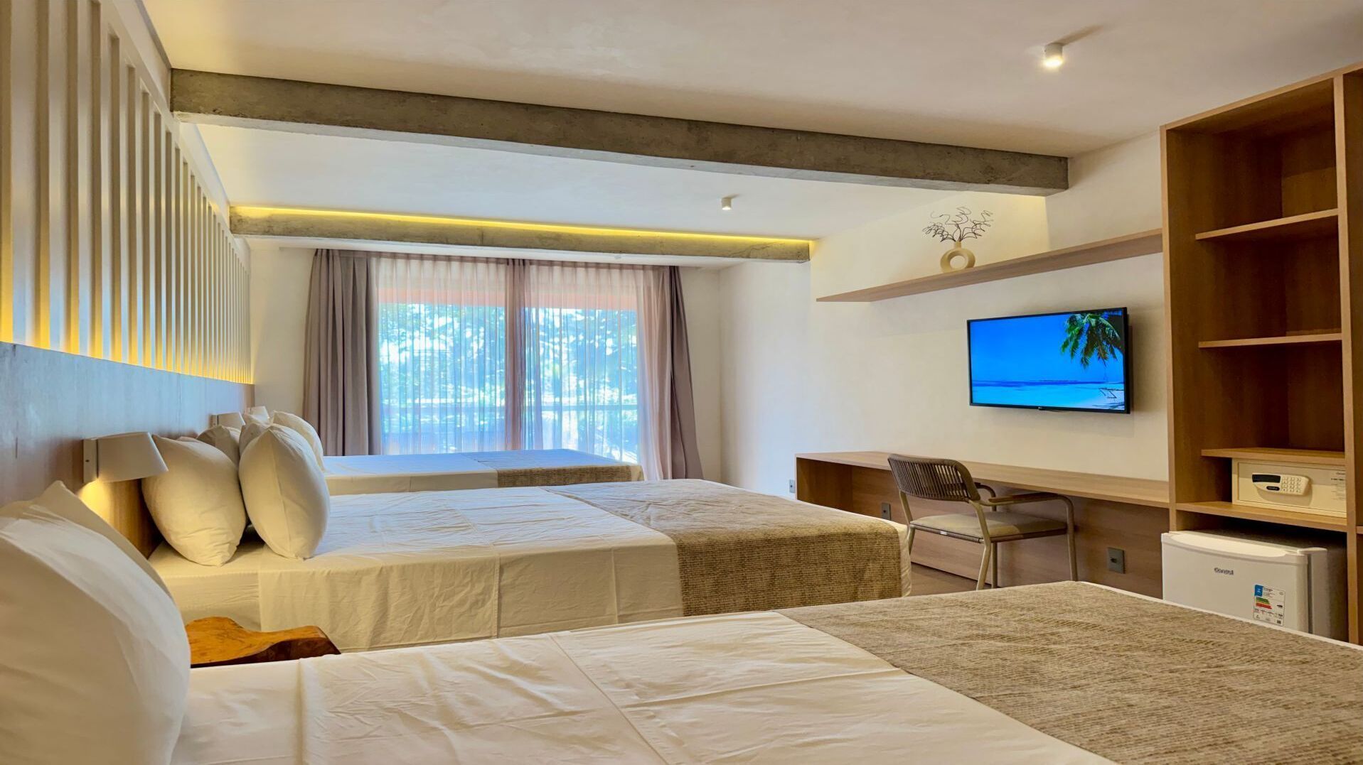 A hotel room with two beds, a desk, a television, and a minibar.