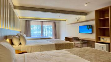 A hotel room with two beds, a desk, a television, and a minibar.