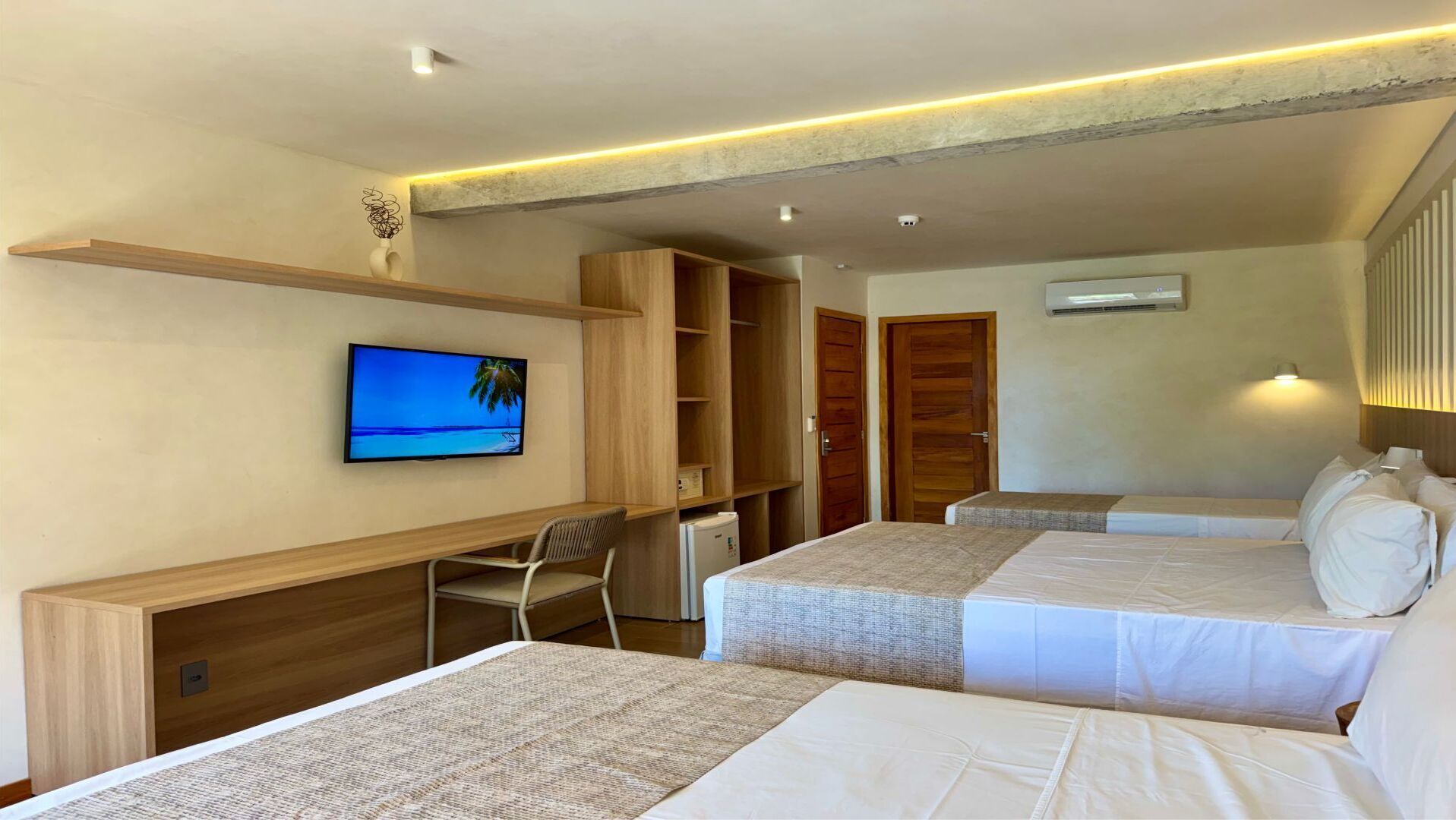 A hotel room with two beds, a desk, a TV, and a wardrobe.